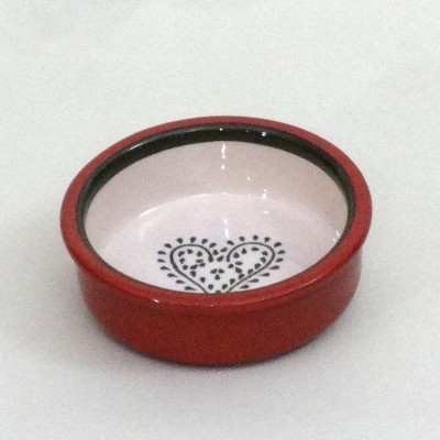 Prato de cerâmica redondo vermelho com padrão de coração preto no centro.