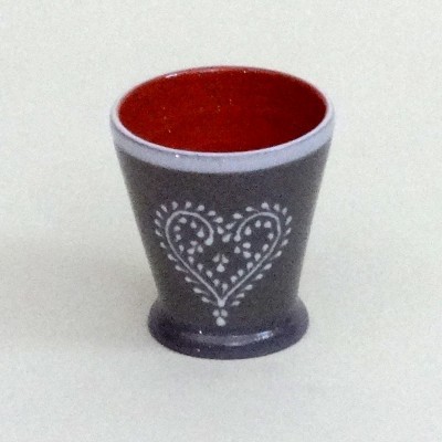 Copo de cerâmica cinza com padrão branco em forma de coração e interior vermelho