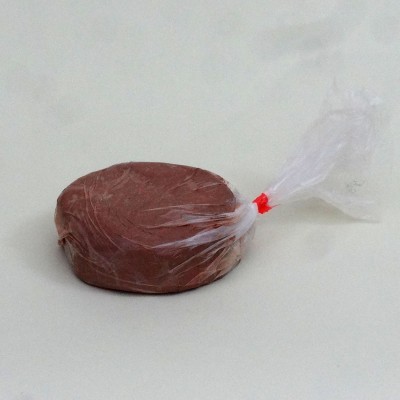 Produto redondo castanho embalado em plástico transparente com fecho vermelho