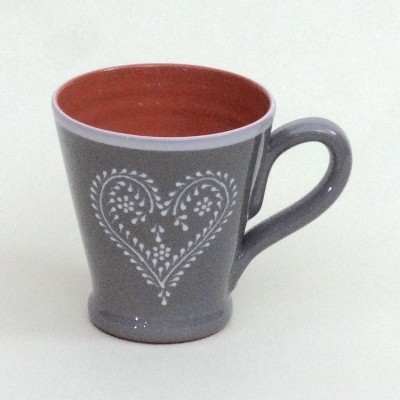 Caneca de cerâmica cinzenta com padrão de coração branco e interior laranja
