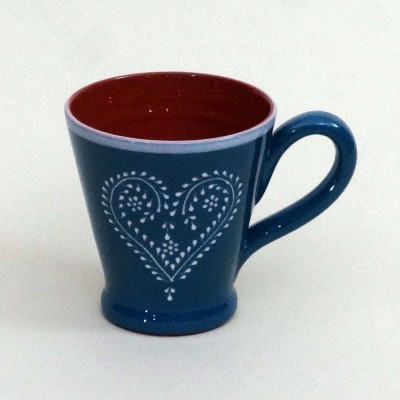 Caneca azul com padrão branco de coração e interior vermelho