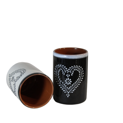 Dois copos cilíndricos de cerâmica, preto e branco, com padrão branco em forma de coração.