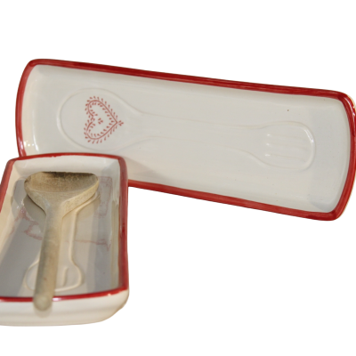 Suporte para colher em cerâmica branca com borda vermelha e desenho de coração com colher de madeira.