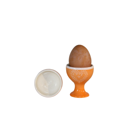 Ovo castanho em suporte de ovo alaranjado com desenho de coração branco