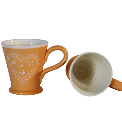 Duas chávenas de cerâmica cor de laranja com decoração de coração branco e interior branco.