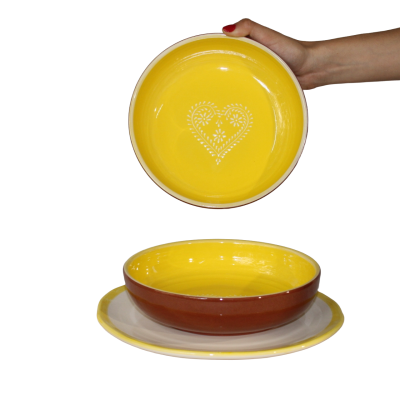 Prato amarelo com coração branco decorativo, prato fundo castanho e plato branco com borda amarela.