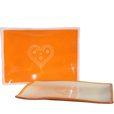 Duas travessas de cerâmica, uma laranja com coração branco e outra creme com borda laranja e coração