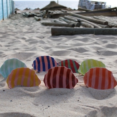 Pratos de cerâmica listrados coloridos na areia da praia