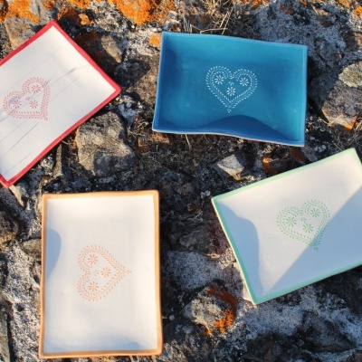 Quatro pratos de cerâmica coloridos com corações decorativos em pedra com líquenes laranja