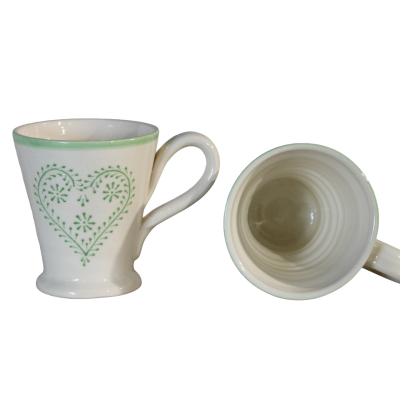 Dois copos brancos de cerâmica com decoração verde em forma de coração e flores.