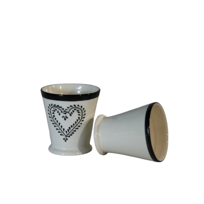 Conjunto de dois copos de cerâmica brancos com borda preta e padrão de coração preto num deles
