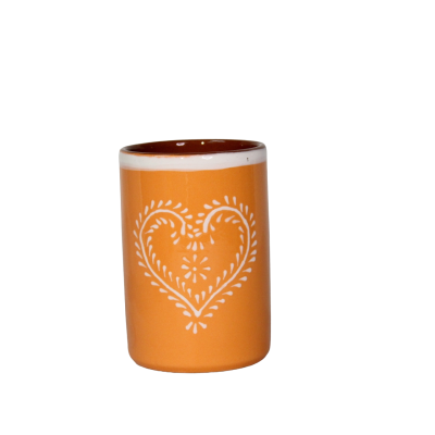 Copo de cerâmica laranja com padrão branco em forma de coração.