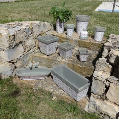 Vasos de cerâmica cinza com padrões geométricos em pedra rústica ao ar livre