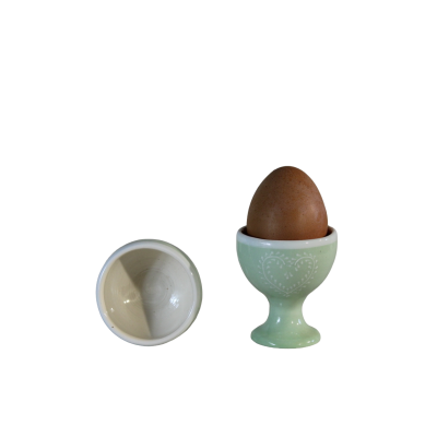 dois copos de ovo cerâmicos, um verde com padrão de coração e um branco