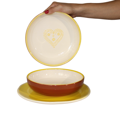 Conjunto de pratos em cerâmica das cores castanho, amarelo e creme com padrão de coração interior.