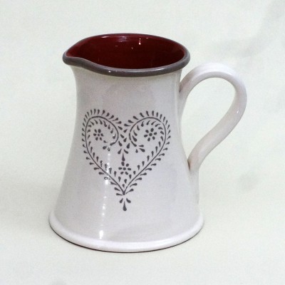 Jarra de cerâmica branca com padrão de coração cinza e interior vermelho.
