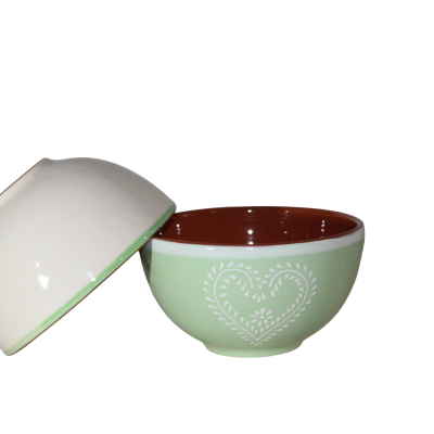 conjunto de duas taças de cerâmica, uma verde clara com padrão de coração branco e interior castanho, outra branca com rebordo verde
