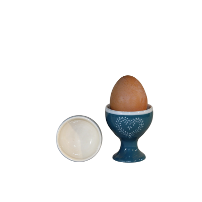 Ovo castanho no suporte azul com padrão branco e tigela de cerâmica branca
