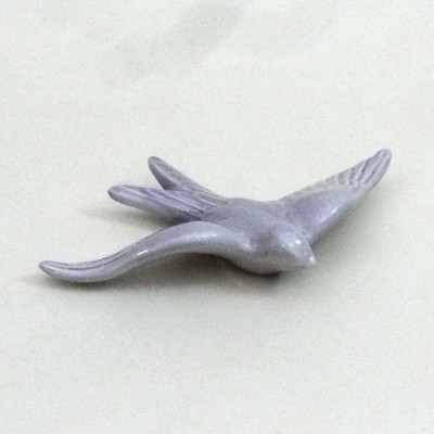 Escultura de pássaro cinzento em cerâmica sobre fundo branco