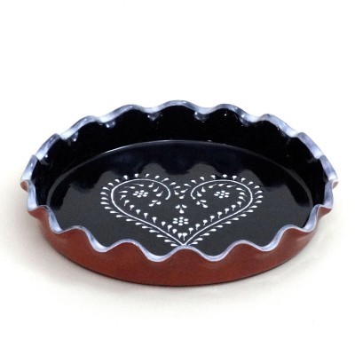 Forma de pão-de-ló redonda em cerâmica com borda ondulada castanha e interior preto com padrão de coração branco