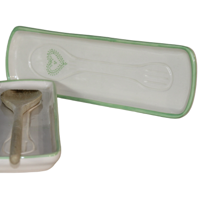 Suporte para colher em cerâmica branca com bordas verdes e decoração de coração verde com colher de madeira.