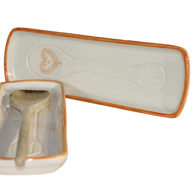 Conjunto de cerâmica branca com bordas cor de laranja e colher de madeira