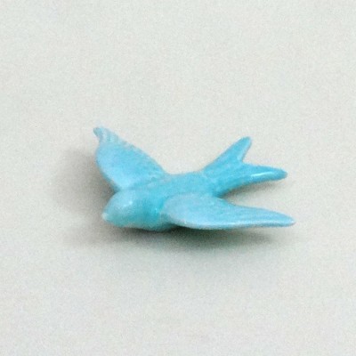 Pequena figura azul de pássaro sobre uma superfície clara