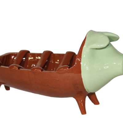 Figurinha cerâmica castanho e verde em forma de porco com corpo aberto e pernas.