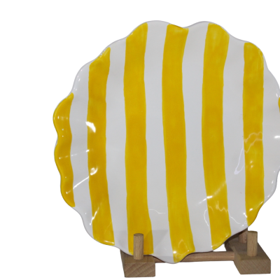 Prato cerâmico ondulado amarelo e branco num suporte de madeira.