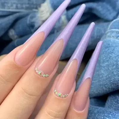 Unhas longas nude com pontas lilás cintilantes e cristais coloridos