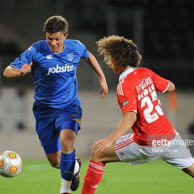 Dois jogadores de futebol em campo, um em azul com logotipo jobsite e outro em vermelho e branco com número 25.