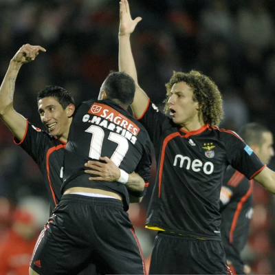 Jogadores de futebol em camisas pretas com logos e números a celebrar no campo