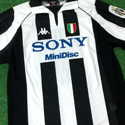 Camisola de futebol com riscas pretas e brancas e logótipos