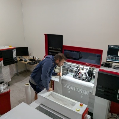 Impressora digital para têxteis com tampa vermelha e branca em espaço interior com homem a observar.