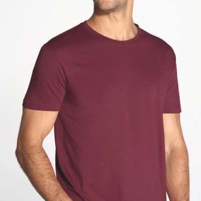 Homem a usar uma camiseta bordeaux de manga curta e calças jeans azuis