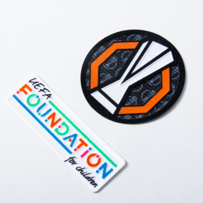 Dois autocolantes, um redondo geométrico e outro retangular com texto colorido UEFA FOUNDATION