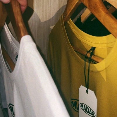 Duas t-shirts penduradas em cabides de madeira dentro de um guarda-roupa