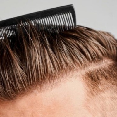 Pente preto a pentear cabelo castanho claro com corte desvanecido