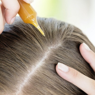 Aplicação de líquido no couro cabeludo de pessoa com cabelo castanho claro