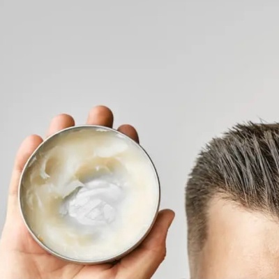 Lata metálica aberta com cera branca cremosa na mão