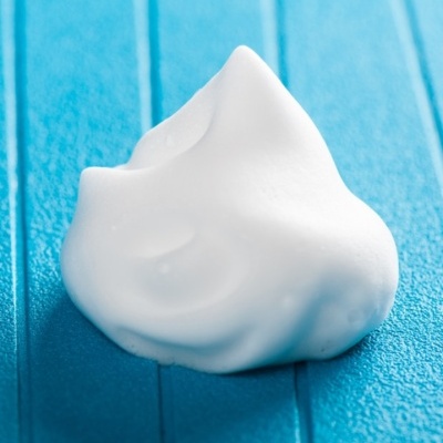 Espuma branca cremosa sobre superfície azul texturizada