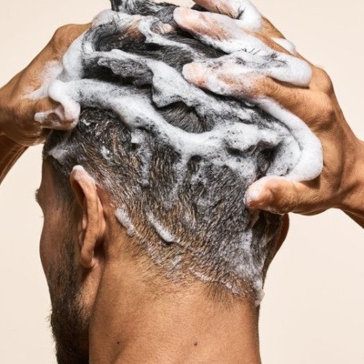 Pessoa a lavar o cabelo com champô e espuma branca