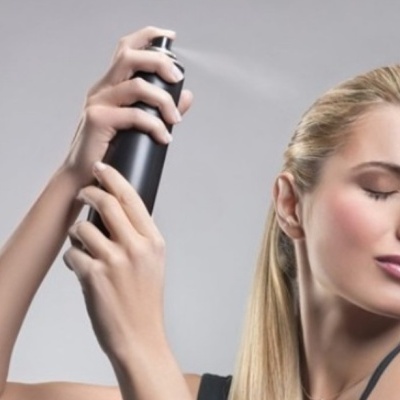 Mulher a aplicar spray fixador de cabelo preto