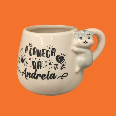 Caneca branca com gato cinzento na alça e texto 'A CANECA DA Andreia'