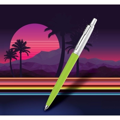 Caneta verde e prateada sobre fundo artístico com palmeiras e pôr do sol
