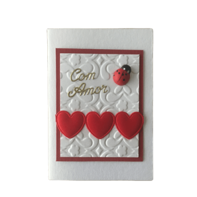 Cartão branco com relevo, corações vermelhos e joaninha com texto Com Amor