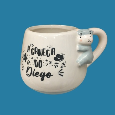 Caneca branca com pega em forma de urso cinzento e texto A CANECA DO Diego
