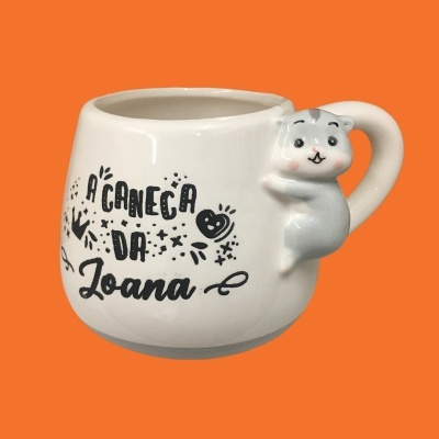 Caneca branca com texto e pega em forma de gato cinzento sobre fundo laranja