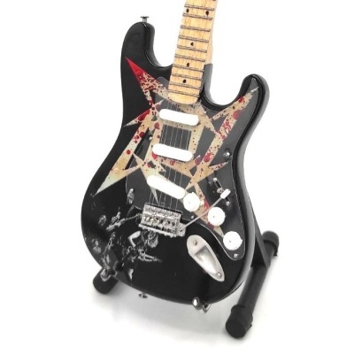 Guitarra elétrica preta com decoração em forma de estrela e figuras, apoiada num suporte preto