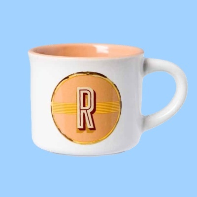 Caneca branca com interior rosa claro e letra 'R' estampada no centro.